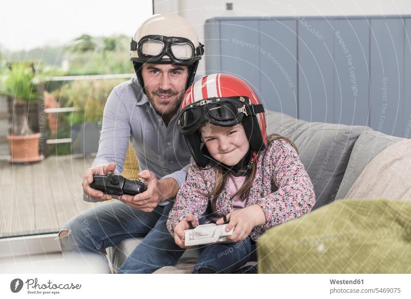 Young man and little girl wearing biker helmets, playing racing game with gaming consoles Competition competitive motorcycle helmet video game video games