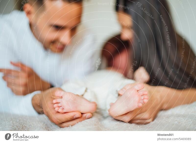 Parents holding baby boy's feet on bed at home color image colour image indoors indoor shot indoor shots interior interior view Interiors day daylight shot