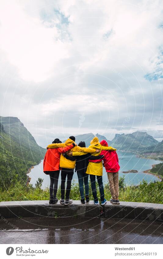 Norway, Senja island, rear view of friends embracing on an observation point at the coast mate viewpoint lookout point standing coastline shoreline embrace