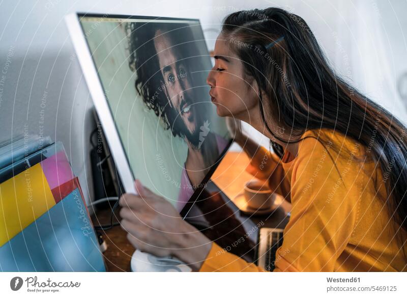 Young woman kissing man on computer screen human human being human beings humans person persons Mixed Race mixed race ethnicity mixed-race Person 2 2 people