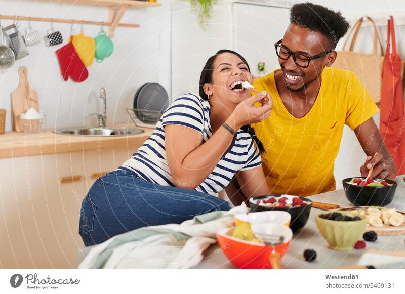 Multiethnic couple breakfasting together in the kitchen funny having fun human human being human beings humans person persons adult grown-up grown-ups grownup
