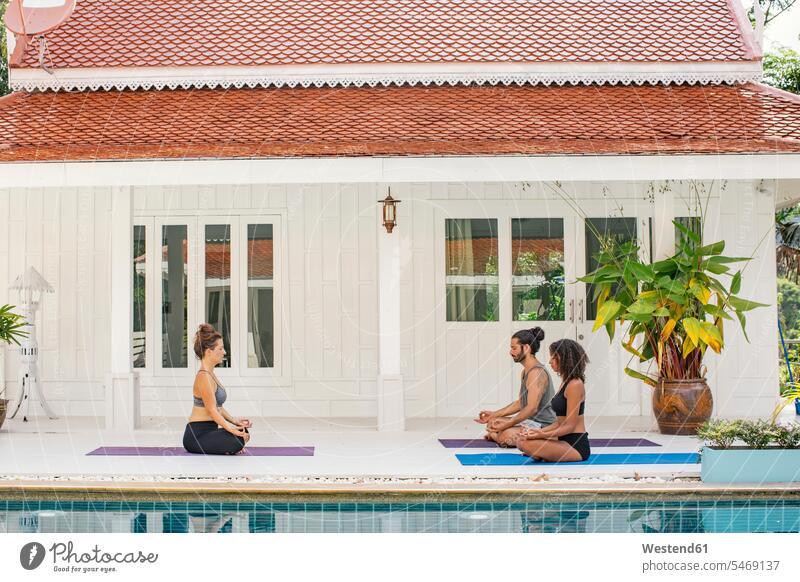 Two women and a man practicing yoga at the poolside pool edge Pool Side swimming pool swimming pools practice practise exercise exercising practising