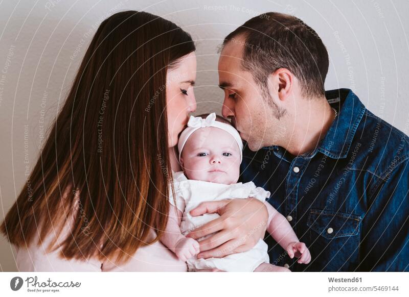 Parents kissing baby girl against wall at home color image colour image indoors indoor shot indoor shots interior interior view Interiors day daylight shot