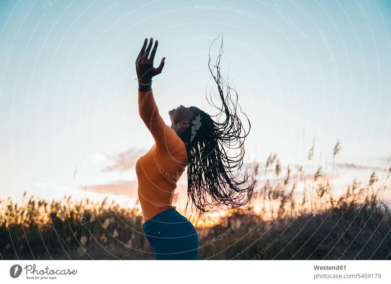 Teenage girl with eyes closed tossing hair in filed during sunset color image colour image outdoors location shots outdoor shot outdoor shots 16-17 years