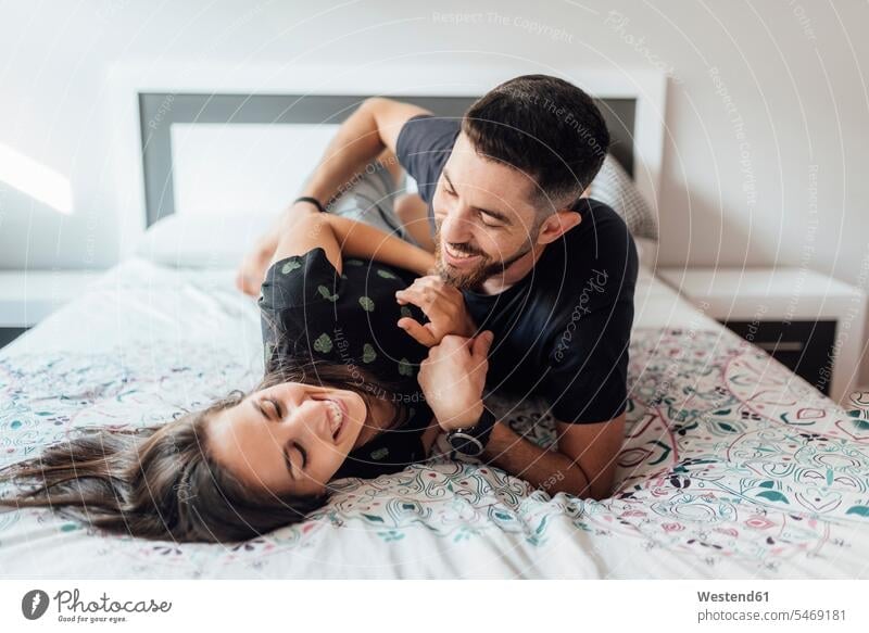 Smiling couple playing on bed in bedroom at home color image colour image indoors indoor shot indoor shots interior interior view Interiors day daylight shot