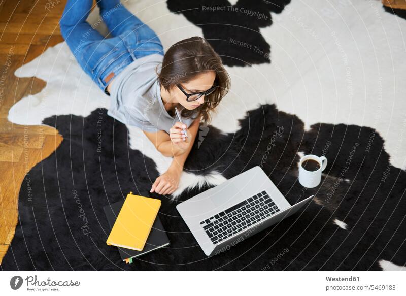 Young woman at home lying on the floor using laptop floors laying down lie lying down Laptop Computers laptops notebook females women computer computers Adults