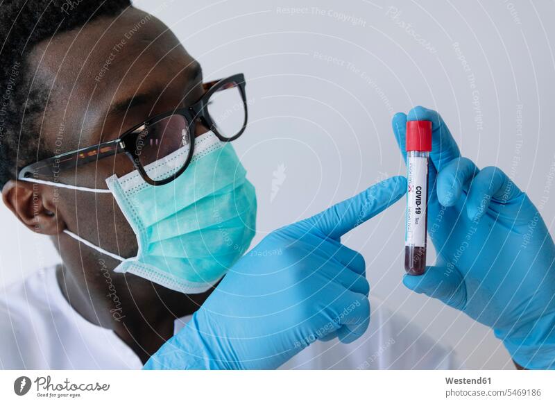 Close-up of afro doctor showing coronavirus blood sample against white background color image colour image Spain white backdrop plain background cut out cutout