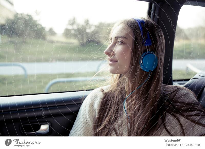 Young woman with windswept hair in a car wearing headphones females women automobile Auto cars motorcars Automobiles headset Windswept Windblown Windy Adults