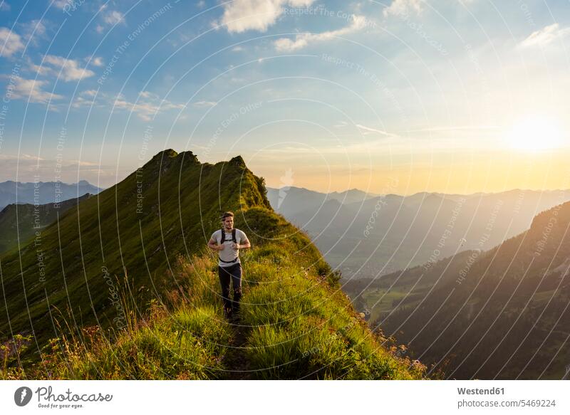 Germany, Bavaria, Oberstdorf, man hiking on a ridge in the mountains at sunset men males sunsets sundown Ridge Mountain Ridge Mountain Ridges hike Adults