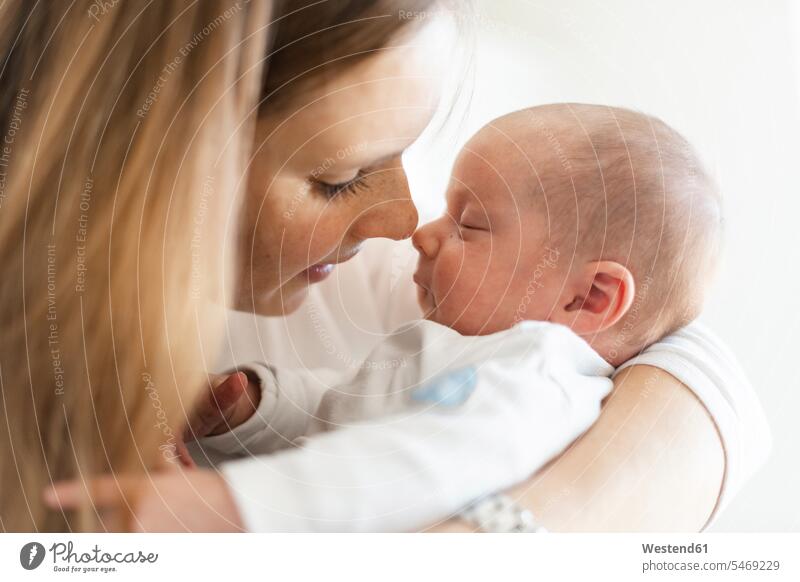 Close-up of mother embracing sleeping baby boy in arms at home color image colour image indoors indoor shot indoor shots interior interior view Interiors day