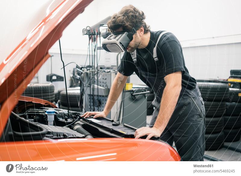 Car mechanic wearing VR glasses in a workshop working at car Occupation Work job jobs profession professional occupation industrial industries machinist