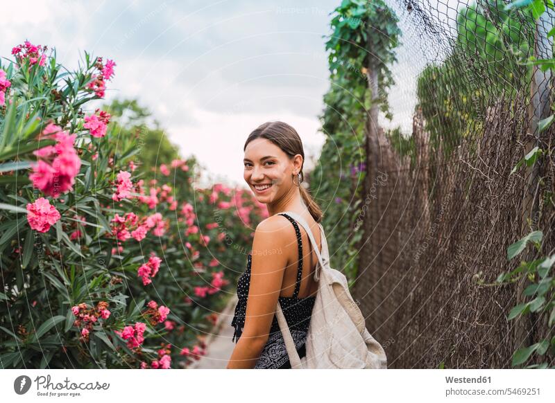 Portrait of smiling young woman with backpack strolling in a park human human being human beings humans person persons caucasian appearance caucasian ethnicity