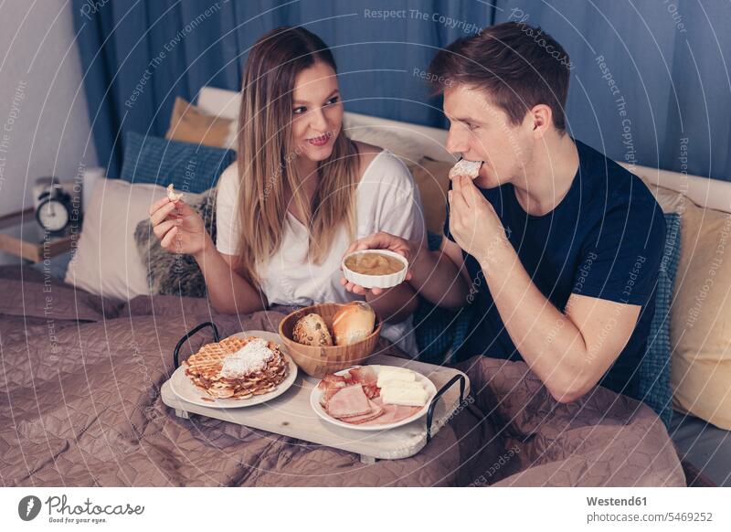 Young couple having breakfast in bed twosomes partnership couples Breakfast beds relaxed relaxation people persons human being humans human beings Meals Food