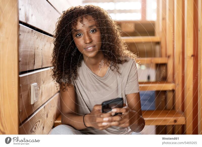 Young woman using mobile phone while sitting on staircase at home color image colour image indoors indoor shot indoor shots interior interior view Interiors day