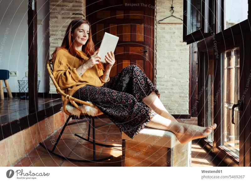 Smiling woman using digital tablet while sitting on chair at home color image colour image indoors indoor shot indoor shots interior interior view Interiors day