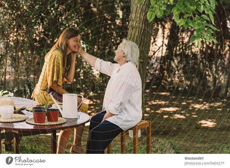 Mother touching daughter's face while sitting in yard color image colour image Spain leisure activity leisure activities free time leisure time casual clothing