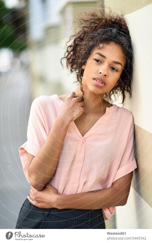 Serious young woman leaning against a wall looking around serious earnest Seriousness austere looking round look round look around walls females women city town