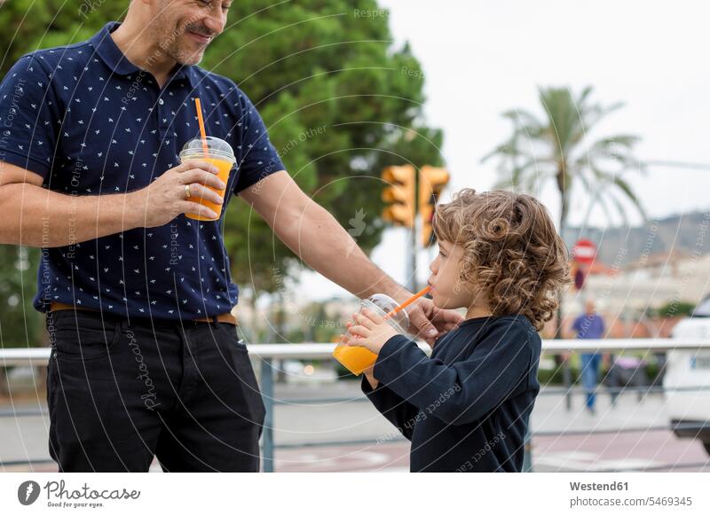 Father and son with soft drinks in the city town cities towns sons manchild manchildren father pa fathers daddy dads papa refreshing drink refreshing drinks