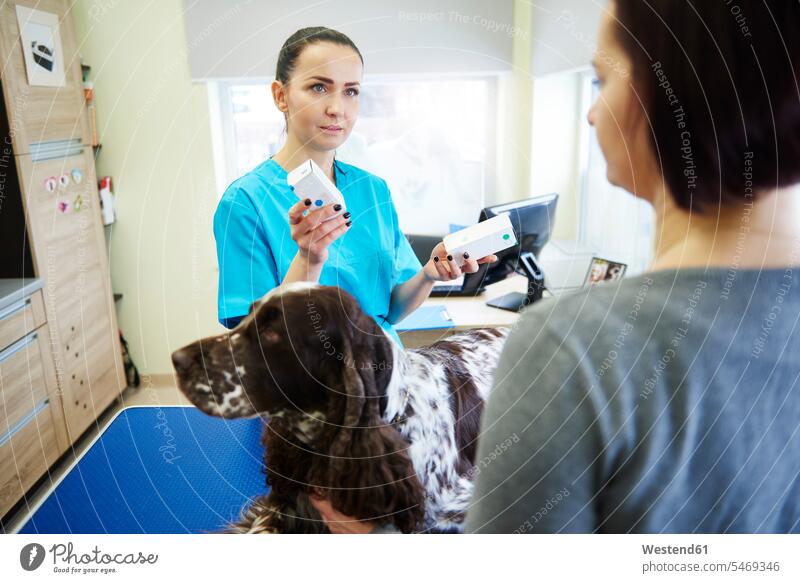 Female veterinarian giving medication to dog owner in veterinary surgery drugs Medicines medicament veterinary practice veterinary office veterinary practices