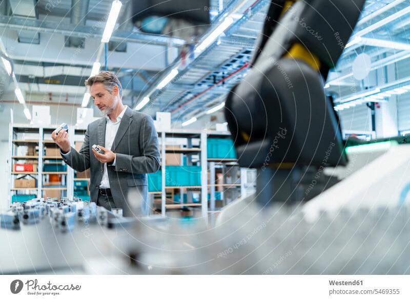 Businessman examining workpieces in a modern factory hall human human being human beings humans person persons caucasian appearance caucasian ethnicity european