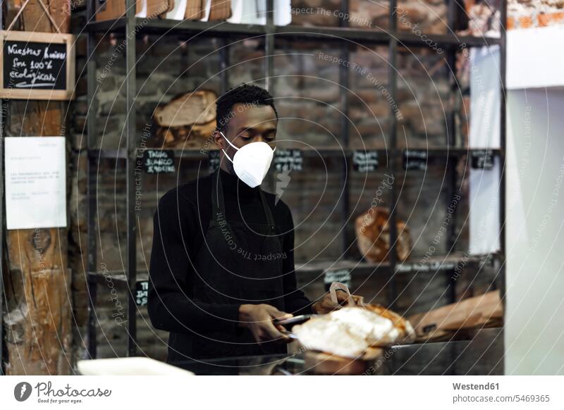 Bakery owner wearing protective face mask while working at bakery color image colour image outdoors location shots outdoor shot outdoor shots day daylight shot