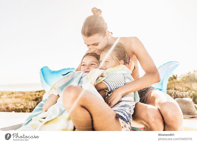 Happy mother caring for her two daughters at the poolside touristic tourists sharks towels toys smile embrace Embracement hug hugging seasons summer time