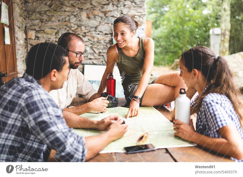 Group of hikers sitting together planning a hiking route looking at map maps friends mate eyeing Seated wanderers group of people groups of people Planning