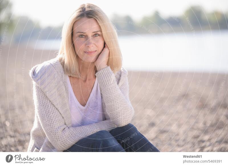 Portrait of smiling mature woman sitting at the riverside resting outdoors outdoor shots location shot location shots attractive beautiful pretty good-looking
