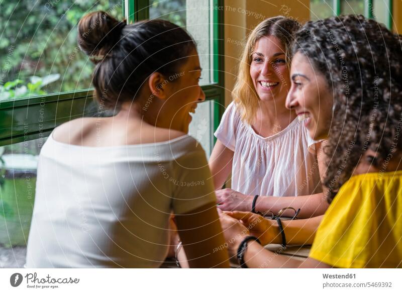 Three happy young women meeting in a cafe human human being human beings humans person persons caucasian appearance caucasian ethnicity european Asian Asians