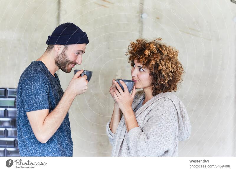 Man and woman drinking coffee and smiling at each other smile females women looking eyeing Coffee Adults grown-ups grownups adult people persons human being