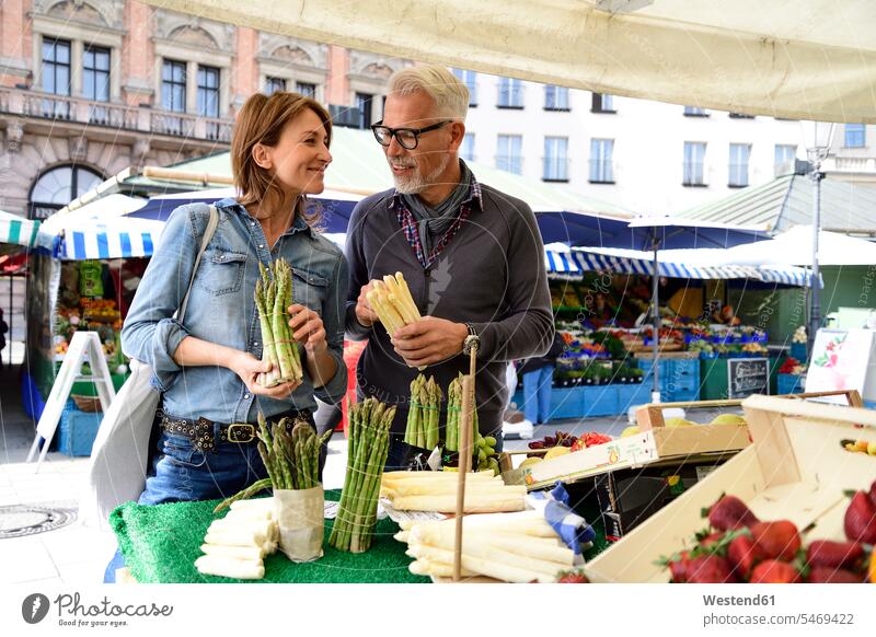 Mature couple choosing asparagus at a market stall human human being human beings humans person persons caucasian appearance caucasian ethnicity european 2
