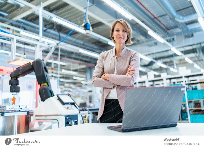 Portrait of confident businesswoman with laptop in a modern factory hall human human being human beings humans person persons caucasian appearance