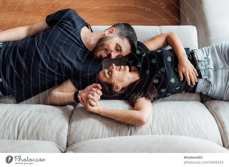 Couple relaxing while lying down on sofa at home color image colour image indoors indoor shot indoor shots interior interior view Interiors day daylight shot