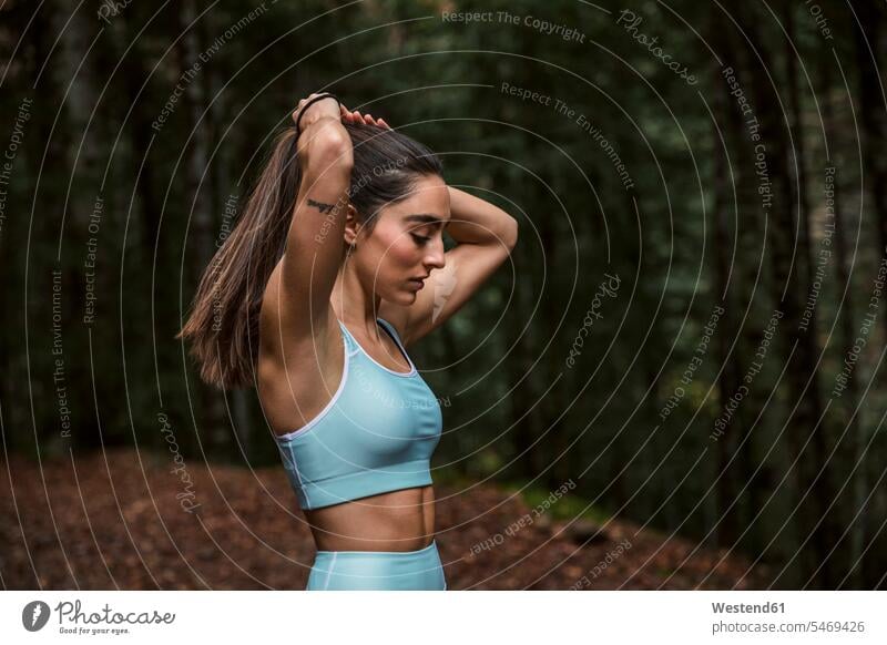 Woman making ponytail while standing in forest color image colour image outdoors location shots outdoor shot outdoor shots day daylight shot daylight shots