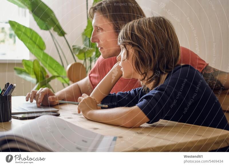 Father and son using laptop while doing homework at home color image colour image indoors indoor shot indoor shots interior interior view Interiors day