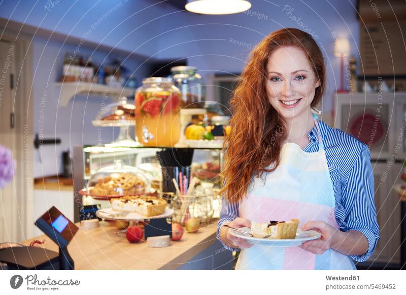 Portrait of smiling young woman serving cake in a cafe serve females women portrait portraits smile pies cakes Adults grown-ups grownups adult people persons