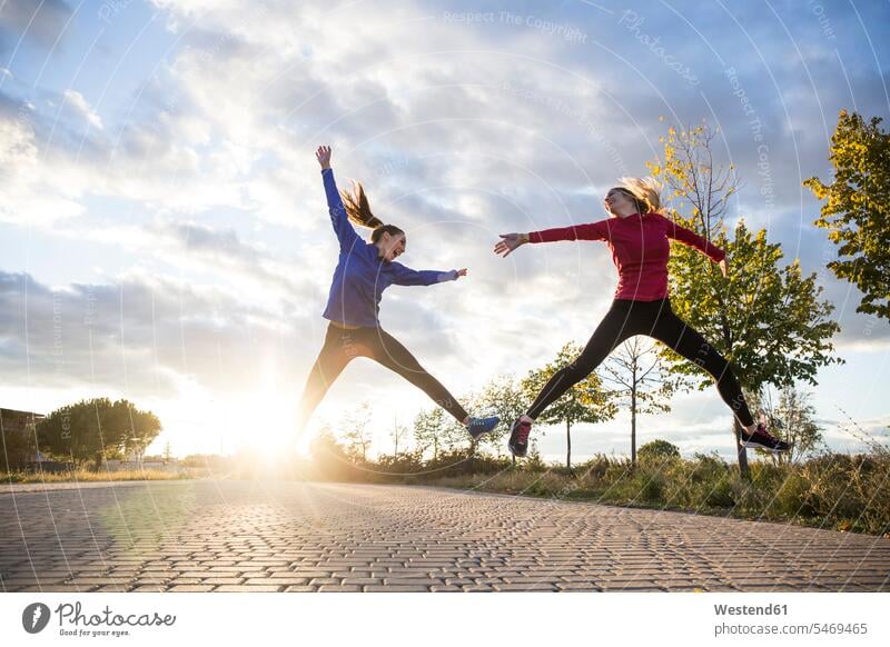 Young women having fun and jumping in park, against morning sun in the morning Ardor Ardour enthusiasm enthusiastic excited delight enjoyment Pleasant pleasure