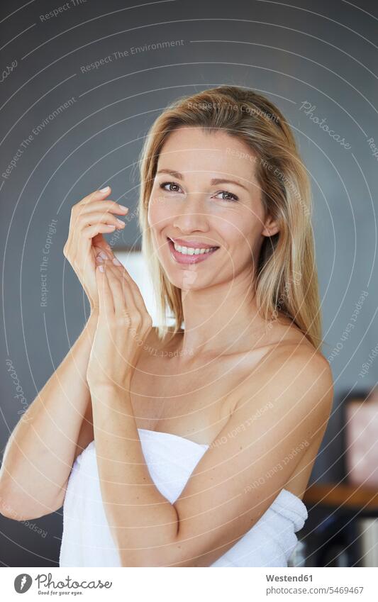 Portrait of smiling blond woman applying face cream in the morning portrait portraits Face Cream facial cream Face Creams smile females women blond hair