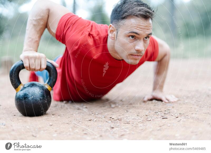 Young athletic man with dumbbell in the woods T- Shirt t-shirts tee-shirt free time leisure time Recreational Activities Recreational Activity