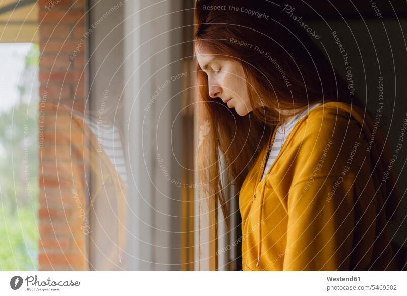 Redheaded woman with eyes closed leaning against window human human being human beings humans person persons celibate celibates singles solitary people