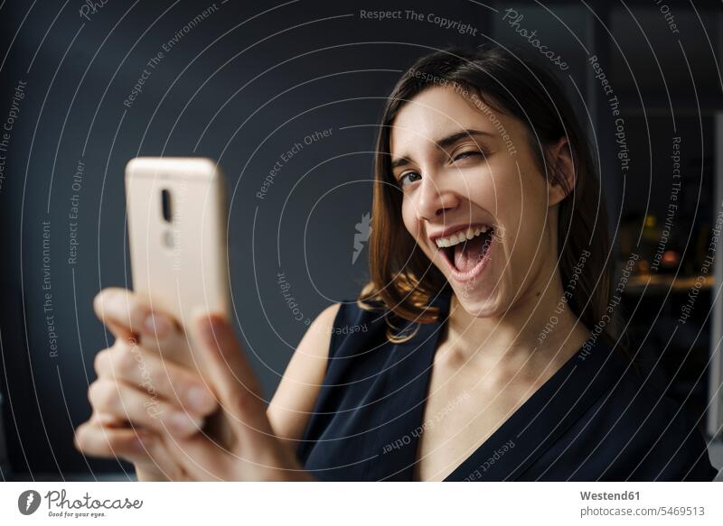 Portrait of young woman with smartphone pulling funny faces dresses telecommunication phones telephone telephones cell phone cell phones Cellphone mobile