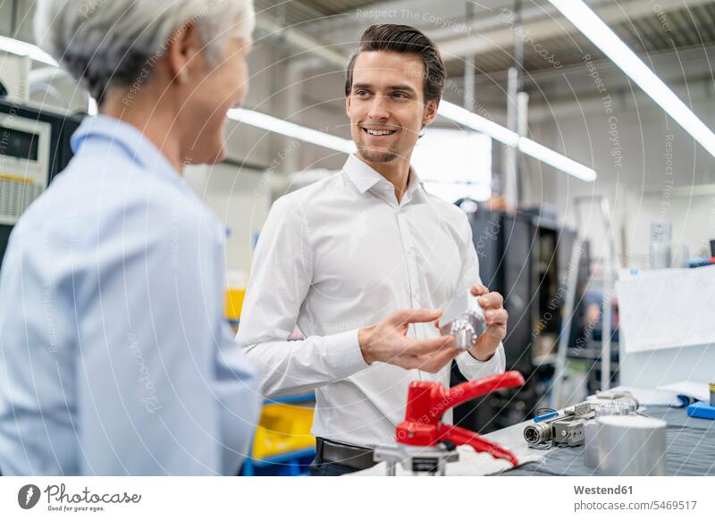 Smiling businessman and senior businesswoman with workpiece in a factory Businessman Business man Businessmen Business men factories businesswomen