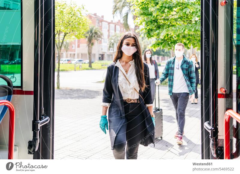 Portrait of young woman wearing protective mask and gloves getting into bus, Spain human human being human beings humans person persons caucasian appearance