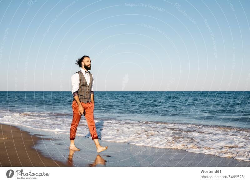 Well dressed man walking on a beach at water's edge human human being human beings humans person persons caucasian appearance caucasian ethnicity european 1