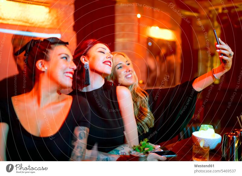 Friends taking selfie while standing at bar counter in pub Night Life Nightlife leisure free time leisure time friendship Disco Discotheque Nightclub Club Party