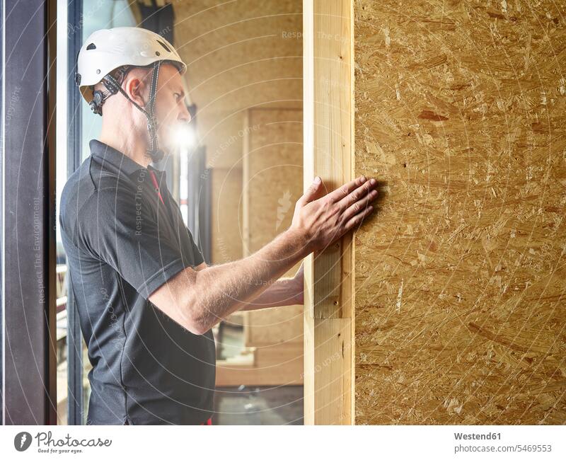 Worker with helmet working with flakeboard At Work flakeboards oriented strand board oriented strand boards OSB man men males worker blue collar worker workers