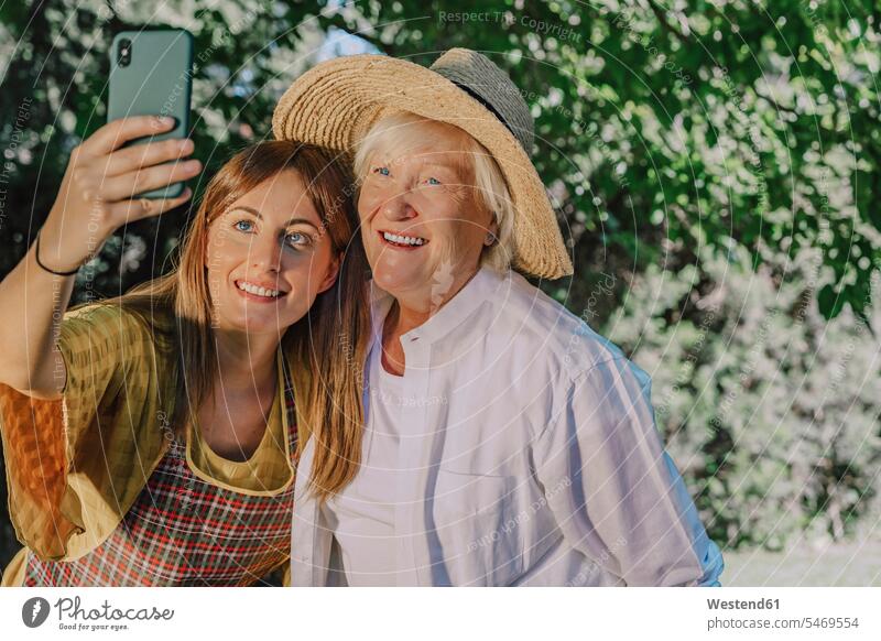 Smiling mid adult woman taking selfie with mother in yard color image colour image Spain leisure activity leisure activities free time leisure time