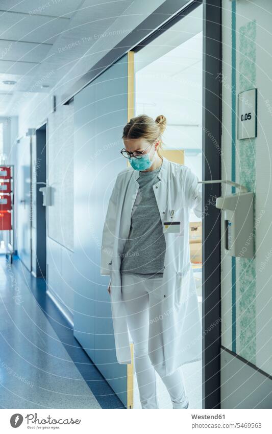 Doctor standing on hospital hallway Occupation Work job jobs profession professional occupation Eye Glasses Eyeglasses specs spectacles At Work contemplative