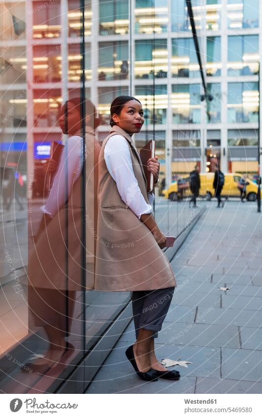 Smiling businesswoman leaning against glass pane looking up businesswomen business woman business women smiling smile glass panes business people businesspeople
