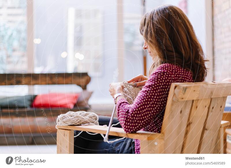 Woman sitting on chair knitting woman females women chairs Seated Adults grown-ups grownups adult people persons human being humans human beings casual